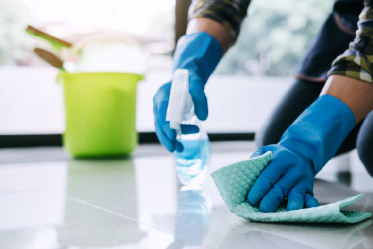 Husband housekeeping and cleaning concept, Happy young man in blue rubber gloves wiping dust using a spray and a duster while cleaning on floor at home Image description